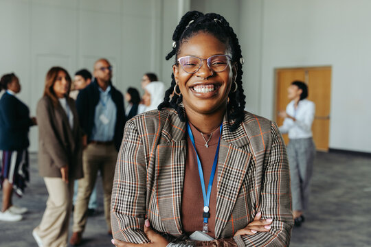 Confident businesswoman laughing at a conference in an office setting with colleagues in the background