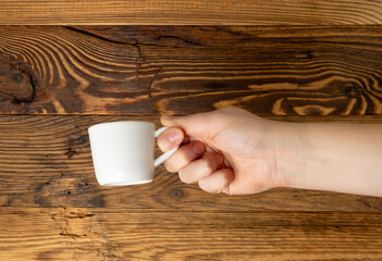 Hand Holds Cup, Empty White Cup in Hands, Coffee Mug, Teacup Mockup, Cup in Arms on Wooden Table