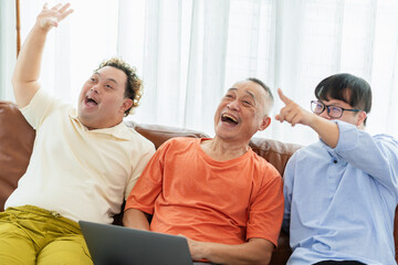 Obraz premium Cheerful grandfather and grandson in living room, Senior asian man having a good time sitting on couch at home with adult son