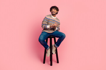 Full body photo of nice young man sit stool look empty space isolated on pink color background