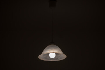 Lit white candlestick in a chandelier on a black background.