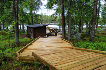 Wooden pathway leading to lakeside cabin in the woods