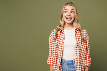 Young shocked surprised impressed amazed woman she wear red shirt white t-shirt casual clothes look aside on area mockup isolated on plain pastel green background studio portrait. Lifestyle concept.