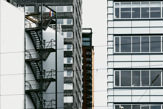 Fire escape ladders are attached to the side of an urban high-rise building, merging safety with architecture and creating a striking geometric pattern.