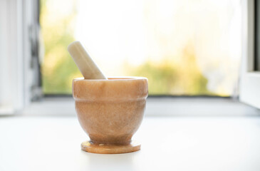 Mortar with spices garlic and pestle on white  table in kitchen