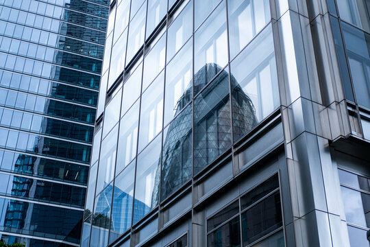 An artistic cityscape scene showing reflections of neighboring buildings on modern glass structures, symbolizing the transparency and interconnectedness of urban life.