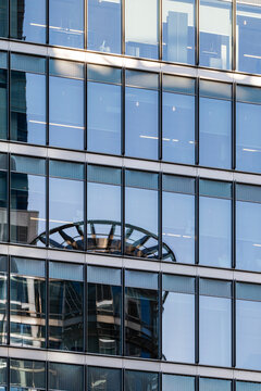 Modern architecture showcasing reflective and clear windows creates intricate patterns with urban industrial elements around. Sleek, cutting-edge design dominates the cityscape.