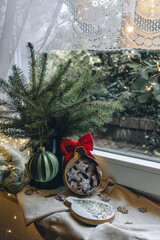 Cozy Christmas still life on the window with fir branches, Christmas cookies and lights.