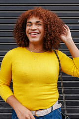 Cheerful transgender woman in yellow clothes posing and smiling to the camera over black background.
