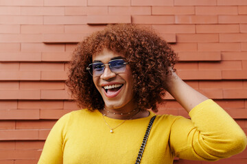 Trans woman with trendy and fashionable outfit smiling to the camera.