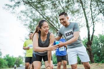 Fototapeta premium male runner offering a bottle of water to exhausted female runner