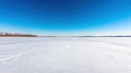 A serene frozen lake beneath a clear, open sky, providing a tranquil winter landscape.