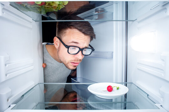 Baffled Man Looking Inside an Almost Empty Fridge