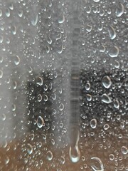 The photo captures a close-up of a window covered in raindrops. The rain creates a delicate texture on the glass, evoking a melancholic mood of a rainy day