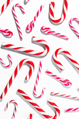 Top view of assorted red and white candy canes on white background vertical composition