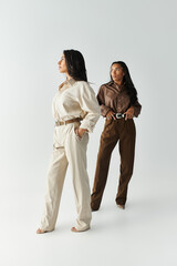Two young women showcase fashionable outfits in a serene, modern setting while posing confidently.