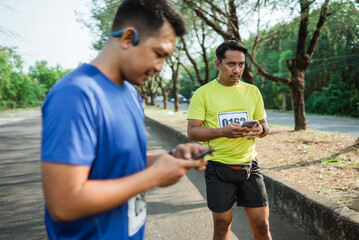 Naklejka premium asian male athlete in sportswear standing and holding phone