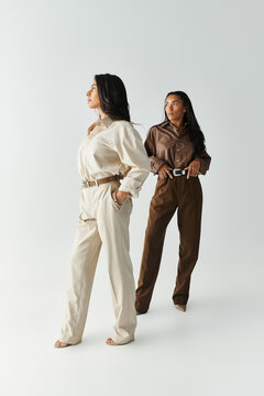 Two young women showcase fashionable outfits in a serene, modern setting while posing confidently.