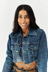 A stylish young woman smiles while showcasing her chic denim ensemble in a modern setting.