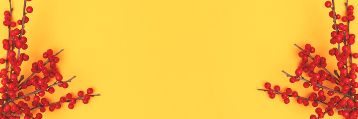 Banner with branches of red winterberry on a yellow background.