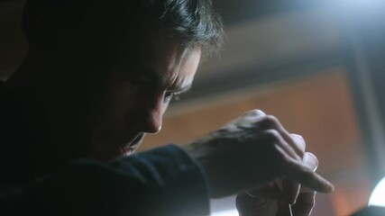 Portrait of focused tanner left handed making holes in leather with puncher tool. Sewing wallet. Piercer punches holes in a piece of skin in his workshop. Concept of entrepreneurship.