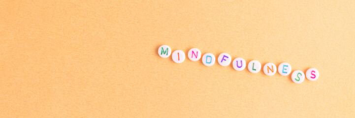 Mindfulness. Banner with word made of round beads with letters on a golden background.