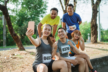 asian marathon athlete taking picture together using handphone