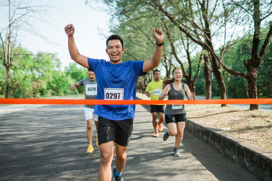 asian male athlete running towards finish line on marathon competition