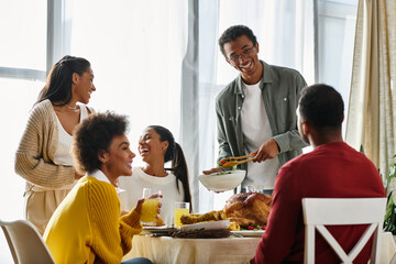 A group of friends celebrates Thanksgiving, enjoying food and laughter in a cozy home setting.