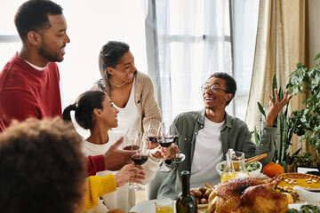 Naklejka premium A group of friends shares laughter and drinks during a cheerful Thanksgiving dinner together.