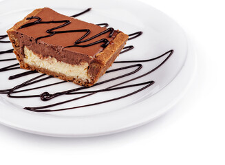 Chocolate tartlet is sitting on a white plate decorated with chocolate sauce