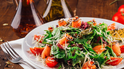 Delicious salad with arugula and salmon served on wooden table