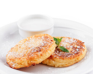 Cottage cheese pancakes with powdered sugar, sour cream and mint on white plate