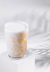 Cold brew coffee with milk and palm leaf shadow on white background