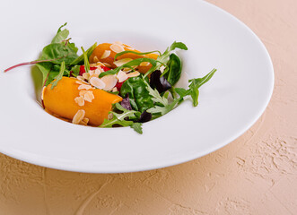 Salad with yellow bell pepper, almond petals and herbs on white plate