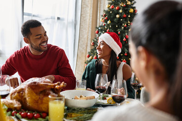 Laughter and cheer fill the living room as friends share a festive meal during Christmas.
