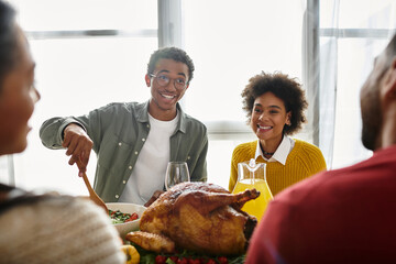 A group of friends shares delicious food and laughter while celebrating Thanksgiving at home.
