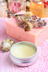 A box with natural body cream and handmade soap on a pink towel.