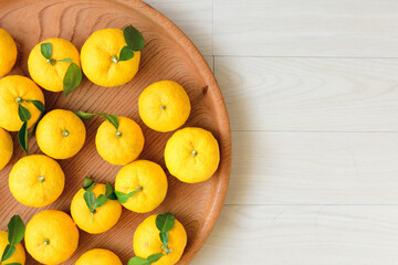 俯瞰で見た、白い背景に木の盆に乗ったたくさんの柚子の実