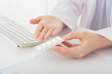 処方薬の説明をする白衣の女性（顔なし）