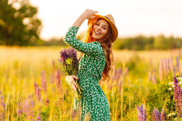 Beautiful woman at purple lavender field with with a bouquet of wild flowers. Concept freedom joy lifestyle. Medicinal herbs.