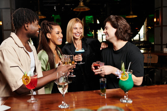A group of young professionals celebrates together, sharing drinks and smiles at a corporate event.