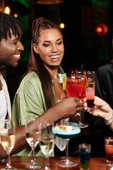 Young diverse professionals celebrate with colorful cocktails at a festive corporate gathering.