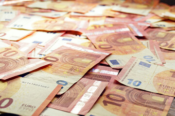 A lot of 10 euro bills randomly laid out on the surface. Cash payments in Europe: a close-up photo of the official currency of the Eurozone countries.