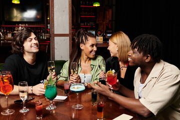A group of diverse young professionals enjoys drinks and laughter at a vibrant corporate gathering.