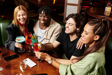 Young professionals joyfully toasting with colorful cocktails at a vibrant corporate celebration.