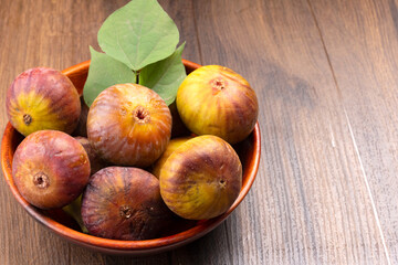 Freshly ripe figs. Healthy Mediterranean fig fruit. Fresh figs on a dark background. Beautiful blue violet figs with leaves, copy space, closeup.