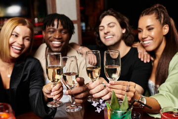 Young colleagues joyfully raise their glasses in celebration at a lively corporate event.