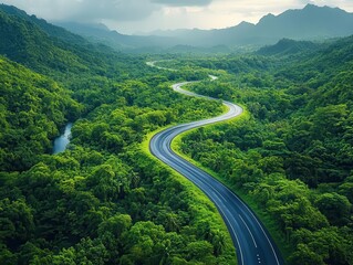 Fototapeta premium a drone's eye view captures a winding highway meandering through a lush forest, highlighting the beauty of nature and the thrill of adventure on a sustainable journey