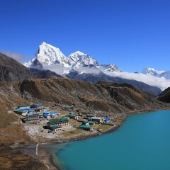 Lodges in Gokyo, turquoise lake and snow covered mountain Cholatse on a autumn day, Nepal.